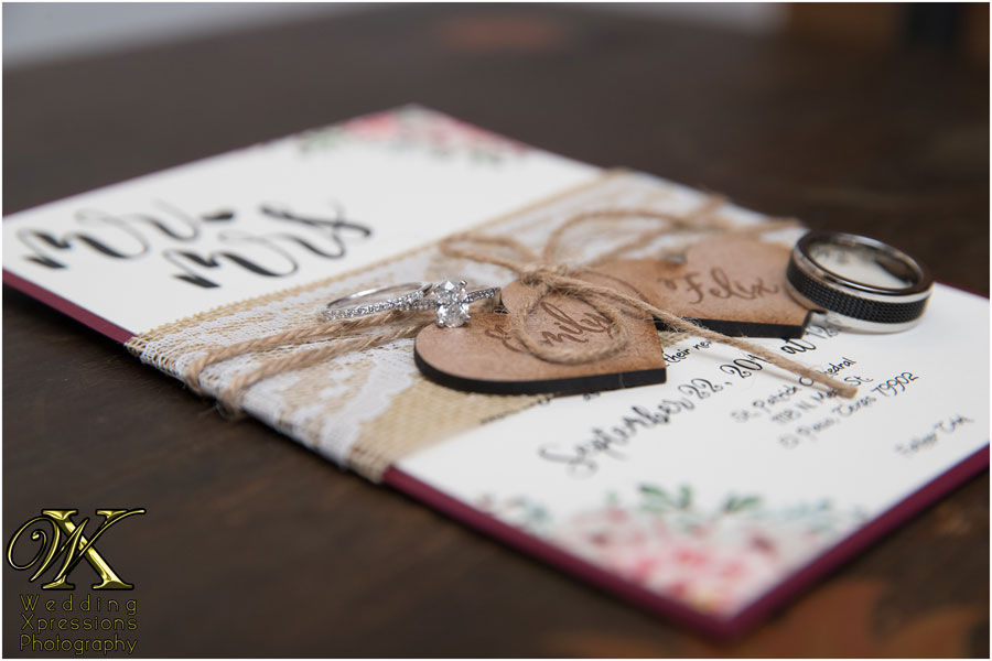 wedding invitation with hearts and their wedding rings placed on top