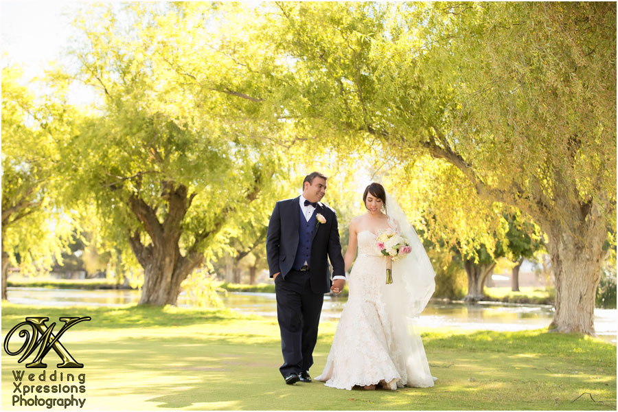 groom in blue suit with bride by lake