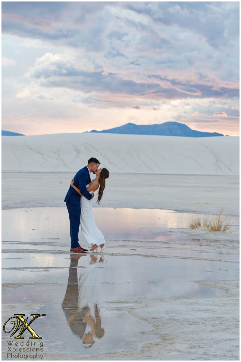 Romantic kiss at White Sands National Park with dramatic stormy sky.