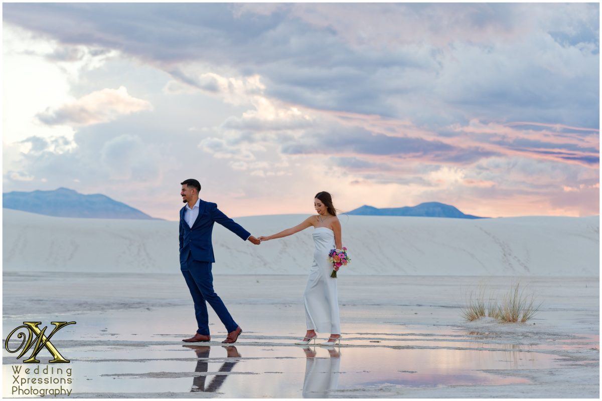Couple running through White Sands dunes during a rainstorm.