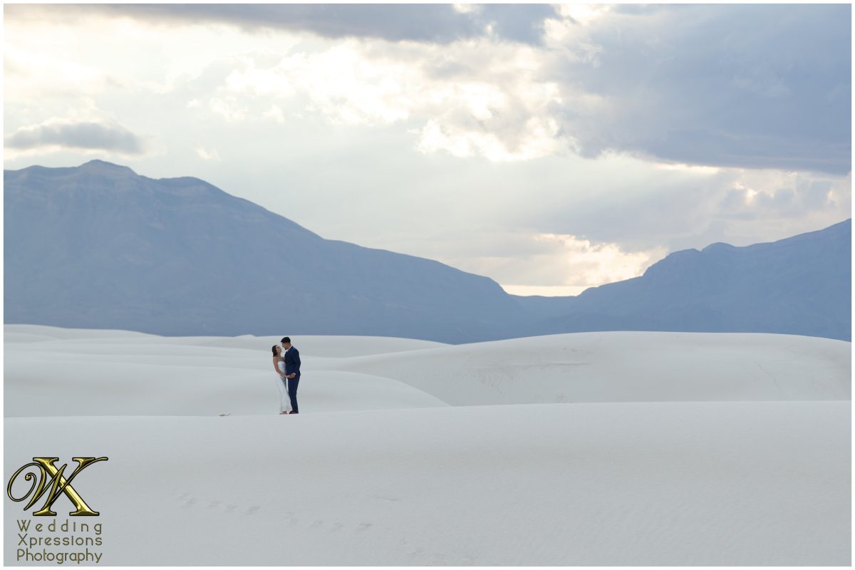 Wide shot of footprints on dunes leading to the engaged couple.