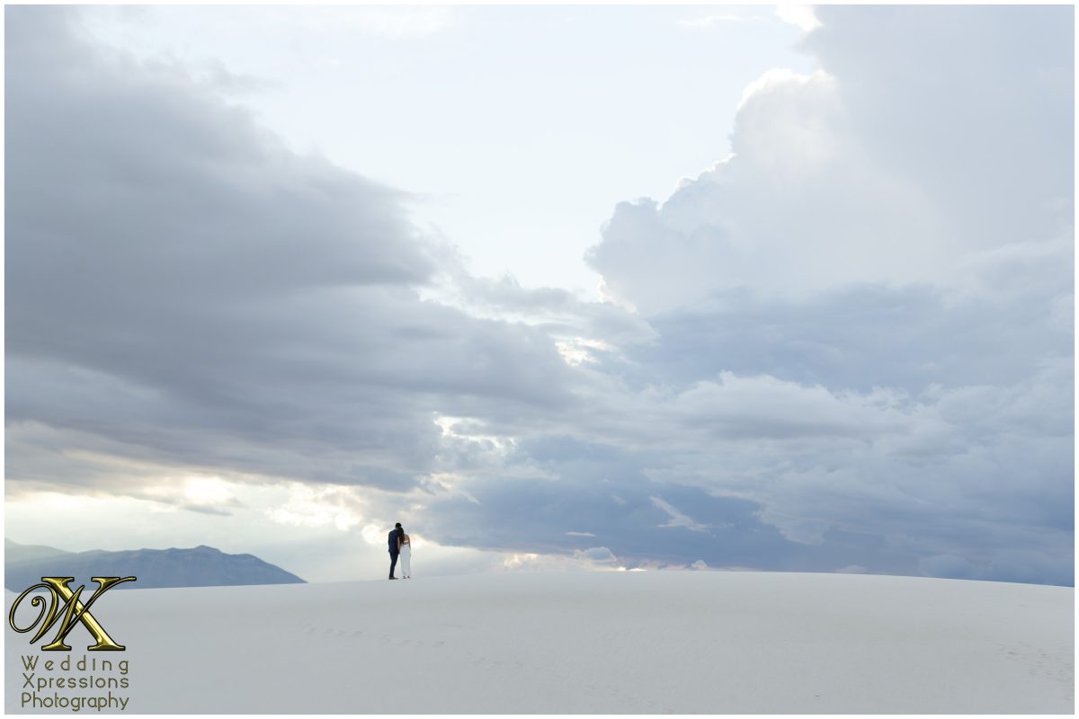 Couple standing small against the vastness of the white sand dunes.