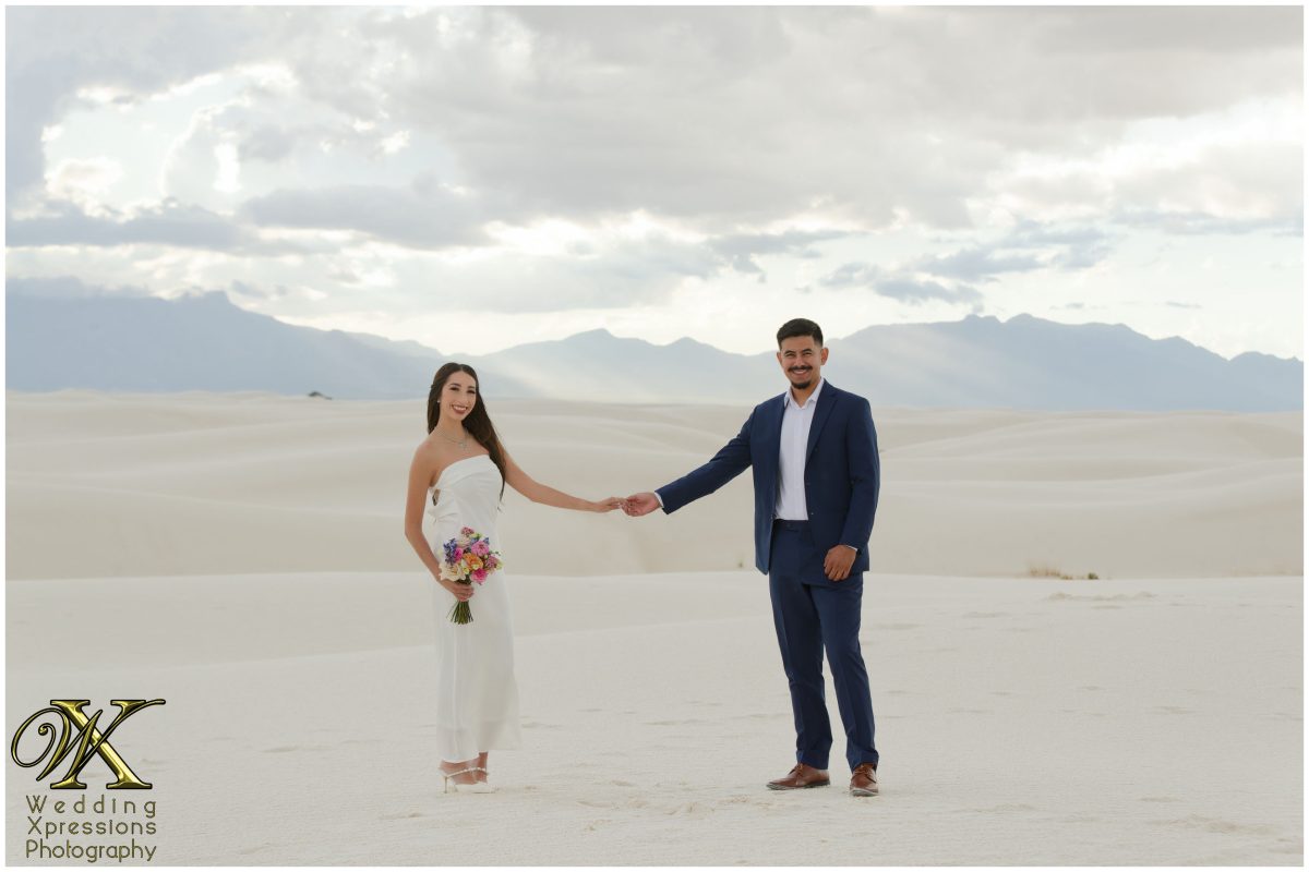 Wide view of the couple walking through the White Sands horizon.