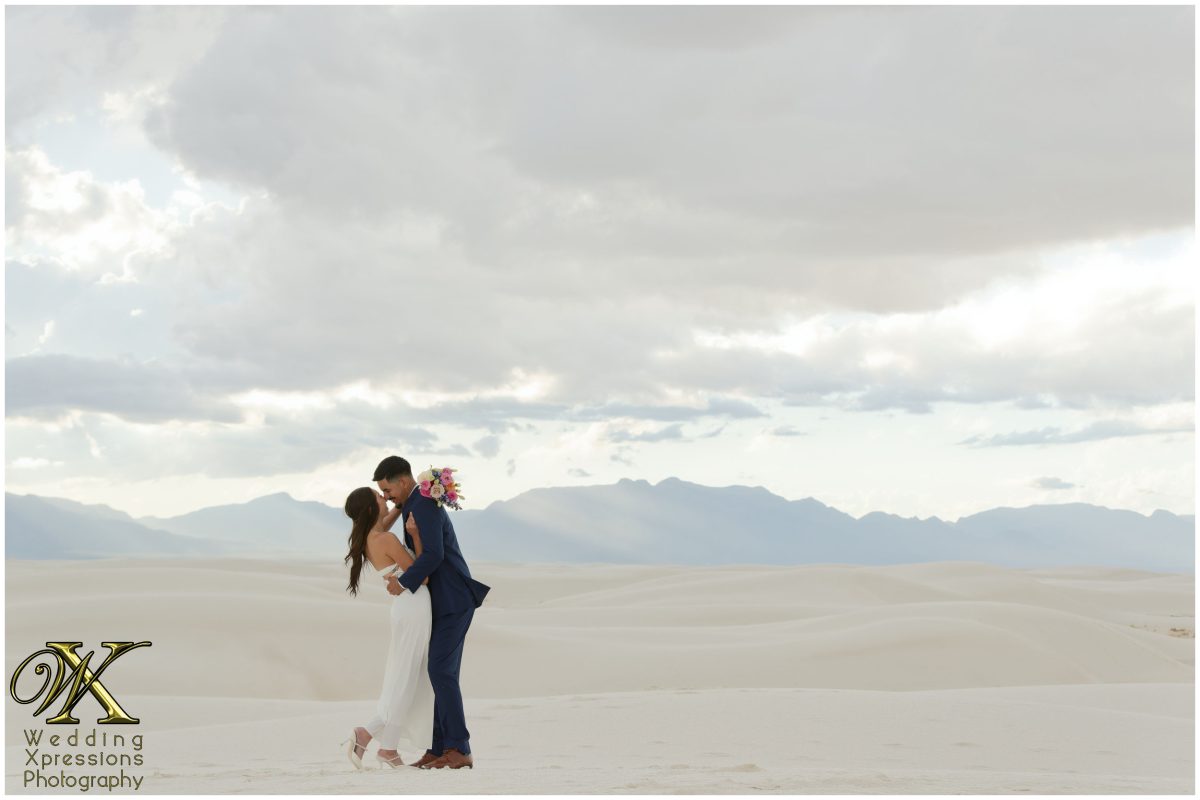 Couple embracing under the wide expanse of the New Mexico sky.