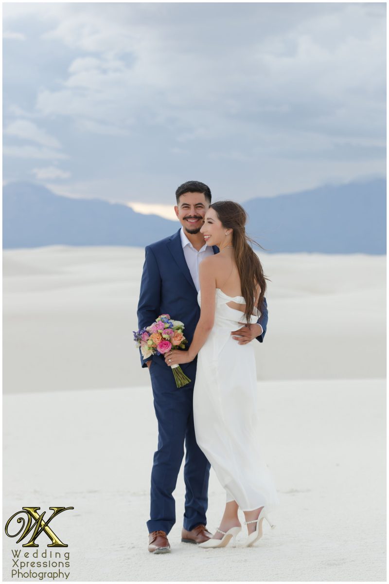 Dramatic wide shot of the couple on a dune crest.