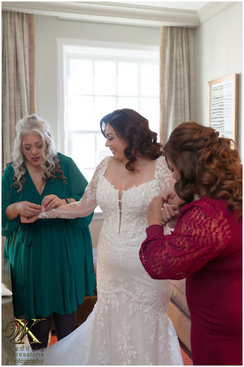 Melissa being helped into her gown by family, a beautiful start to her wedding legacy.