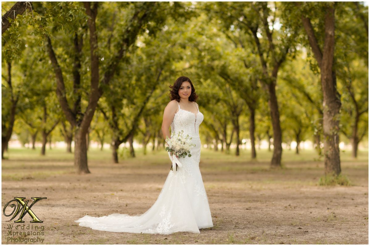 Melissa standing elegantly among the pecan trees, showcasing her stunning bridal style.