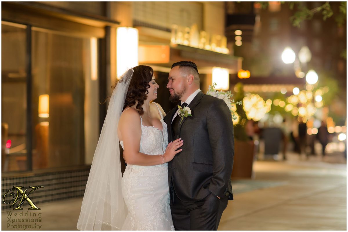 The couple embracing against the vibrant city lights of El Paso at night.