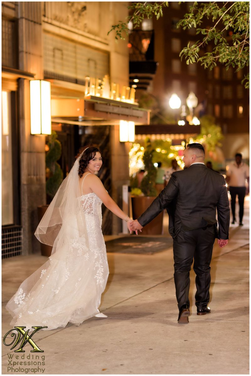Christian and Melissa walking hand-in-hand through the urban night landscape.